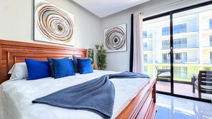 Ein Hotelzimmer mit einem großen Bett, einem Holzkopfstück und zwei abstrakten Bildern an den Wänden.