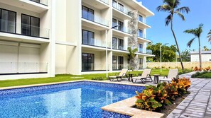 Ein modernes Hotel mit Schwimmbad, Liegestühlen und einem gepflegten Rasen.