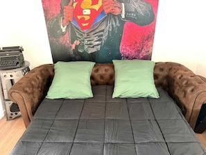 A room with a tufted brown sofa, two green pillows, and a black mattress. - Le Jules Verne, centre Amiens, parking, Wi-Fi (Amiens)