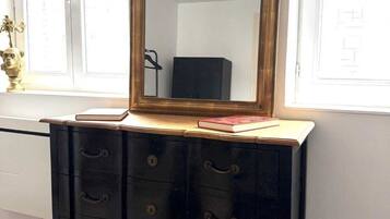 A dresser with a mirror, drawers, and a small vase with a plant on top.