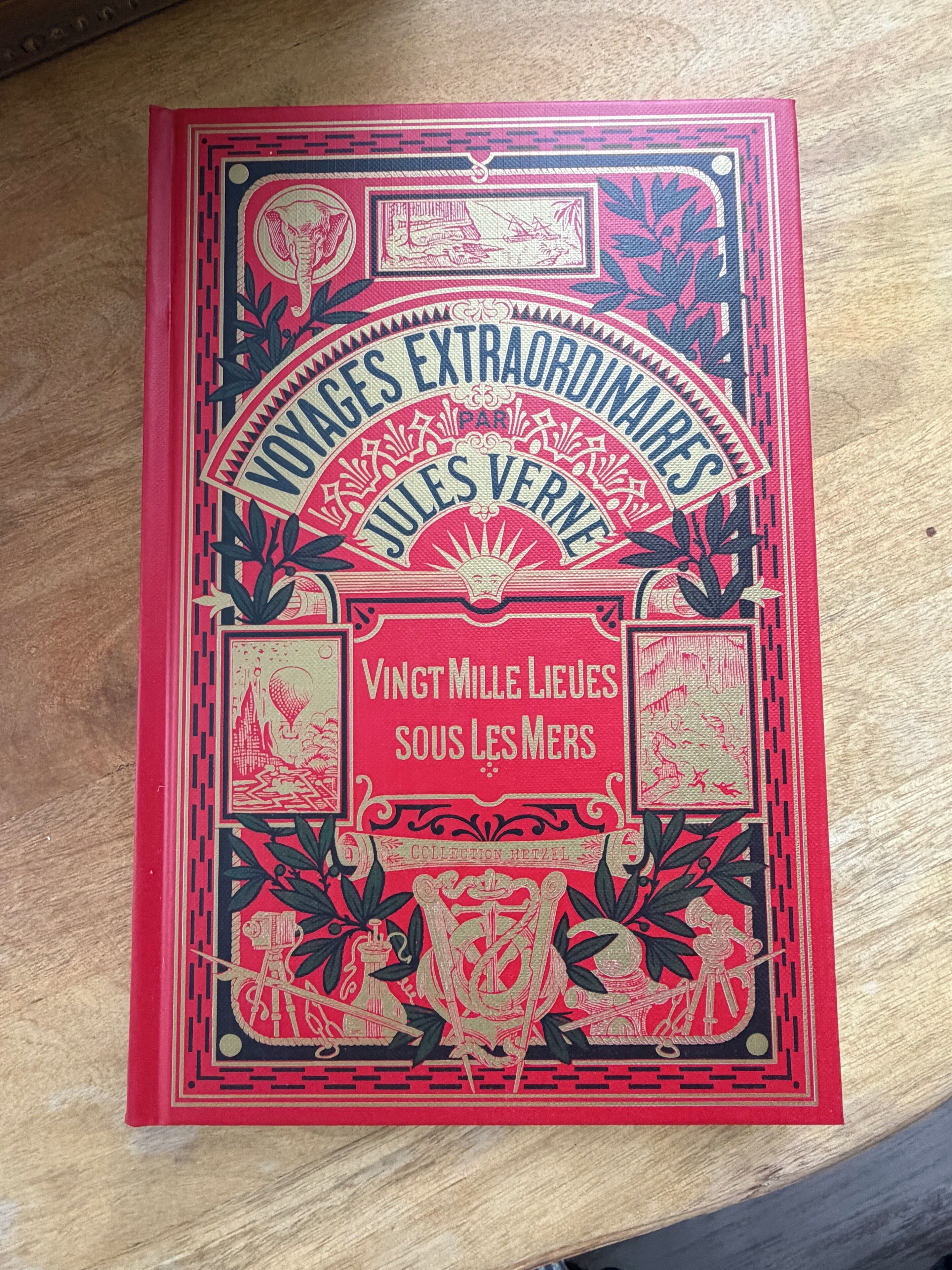 Een boek met de titel 'Voyages Extraordinaires Jules Verne', met decoratieve illustraties en tekst.