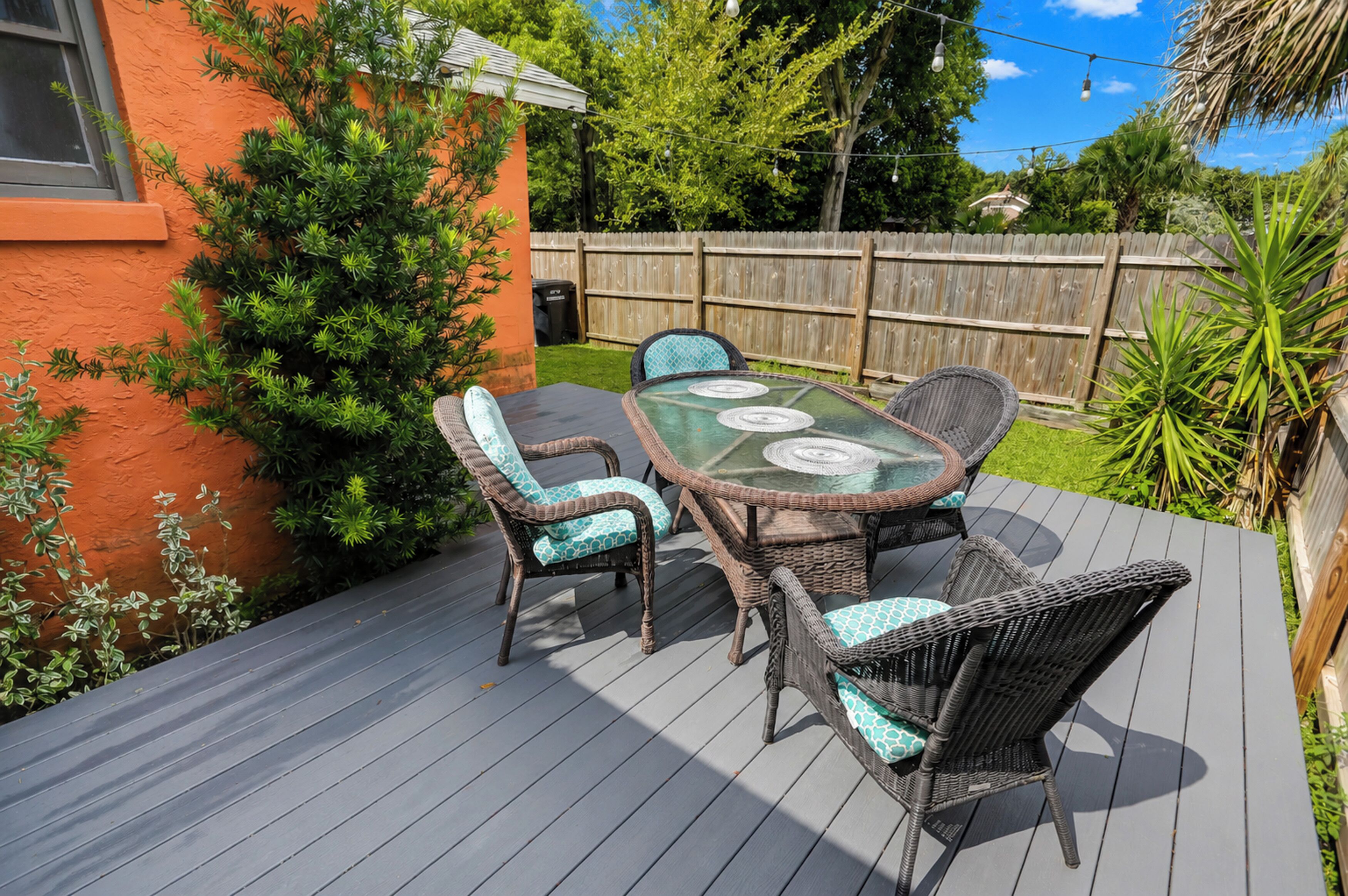 Une terrasse extérieure avec une table à plateau de verre et des chaises en osier.