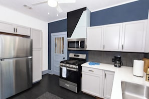 A modern kitchen with stainless steel appliances, white cabinetry, and a dark blue accent wall. - Charming 3BR/2BA Retreat West Downtown Pensacola (Pensacola)