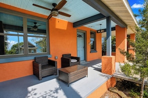 An outdoor seating area with wicker furniture, a ceiling fan, and a door leading to the interior. - Charming 3BR/2BA Retreat West Downtown Pensacola (Pensacola)