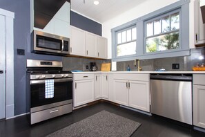A modern kitchen with stainless steel appliances, white cabinetry, and a large window. - Charming 3BR/2BA Retreat West Downtown Pensacola (Pensacola)