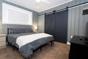 Ein Schlafzimmer mit einem Bett, Nachttischen, einem Kleiderschrank, einem Schreibtisch und einem Fenster.