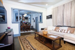 A living room with a sofa, coffee table, and a dining area with chairs and a table. - Charming 3BR/2BA Retreat West Downtown Pensacola (Pensacola)