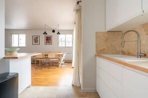 A modern kitchen with a wooden countertop, a sink, and a dining area with chairs. - Paris 15 Gem - 140m2, Terrace, Parking (Paris)