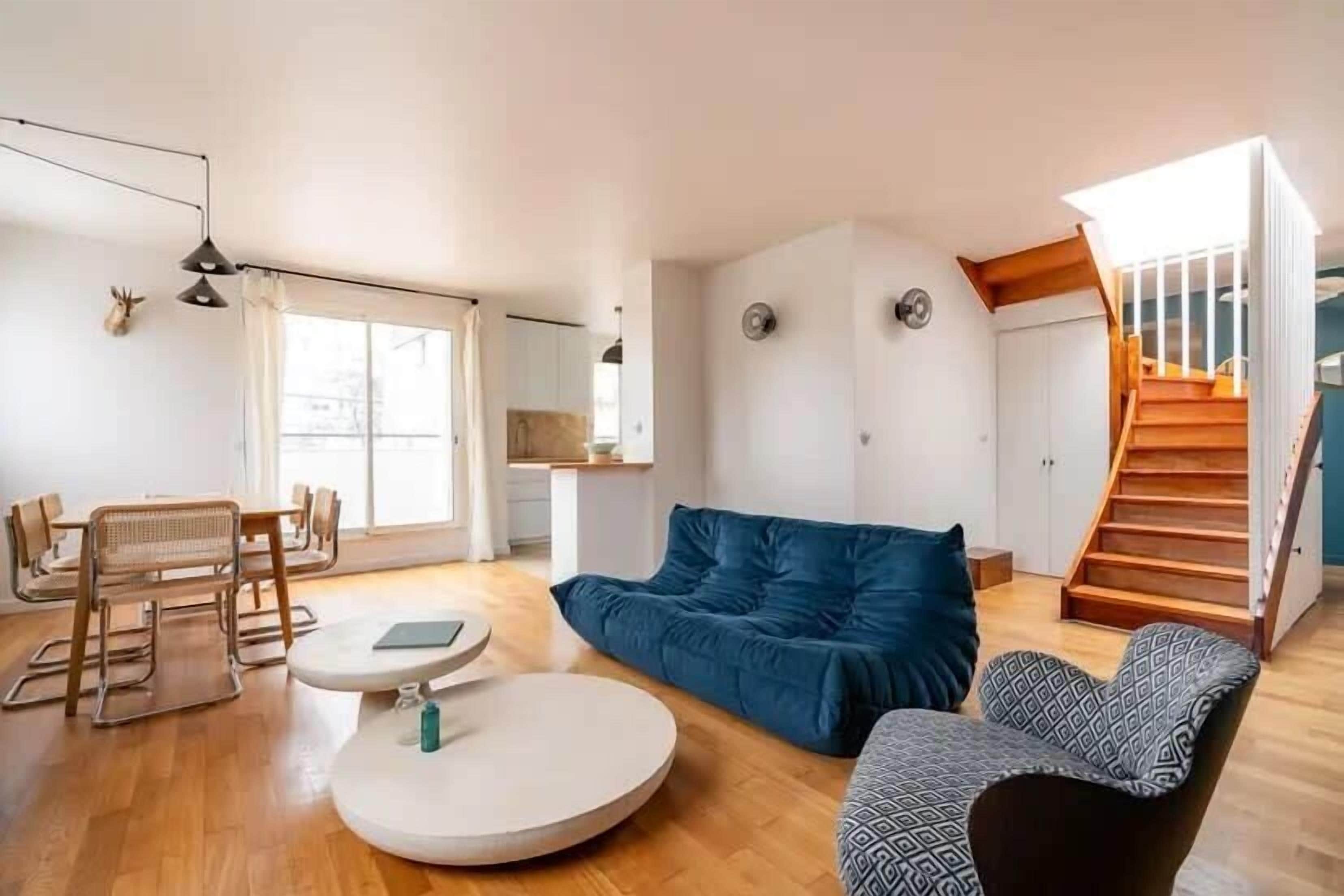 A modern living room with a sofa, a round table, and a staircase.