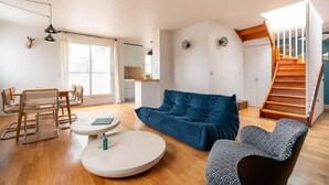 Uma sala de estar moderna com um sofá, uma mesa redonda e uma escada.