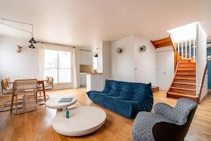 A modern living room with a sofa, a round table, and a staircase. - Paris 15 Gem - 140m2, Terrace, Parking (Paris)