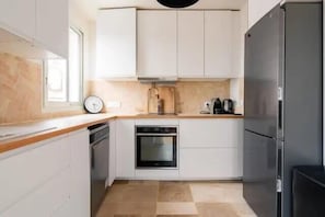 A compact kitchen with white cabinets, a stainless steel refrigerator, and a built-in oven. - Paris 15 Gem - 140m2, Terrace, Parking (Paris)