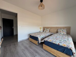 Ein Schlafzimmer mit zwei Betten, einem Nachttisch mit Lampe und einer Pendelleuchte.