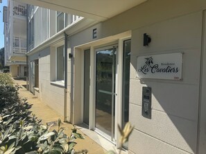Ein Gebäudeeingang mit einem Schild, auf dem 'Residence Les Cavadiers' steht, und einem Sicherheitstastfeld.