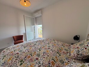 A bedroom with a bed, a chair, a bedside table, and a window with a view. - 2-bedroom apartment with balcony, close to the sea (Cabourg)
