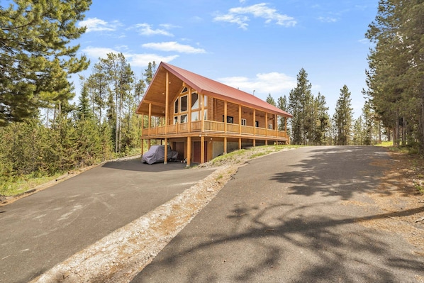 A wooden cabin with a balcony, surrounded by trees.