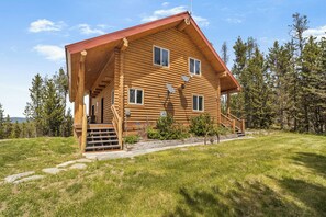 A log cabin with a porch, a staircase, and satellite dishes.