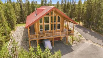 A log cabin with a red roof, large windows, and a porch.