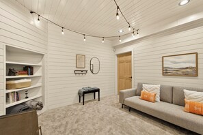 A room with a grey sofa, a bookshelf, a small table, and a mirror on the wall.