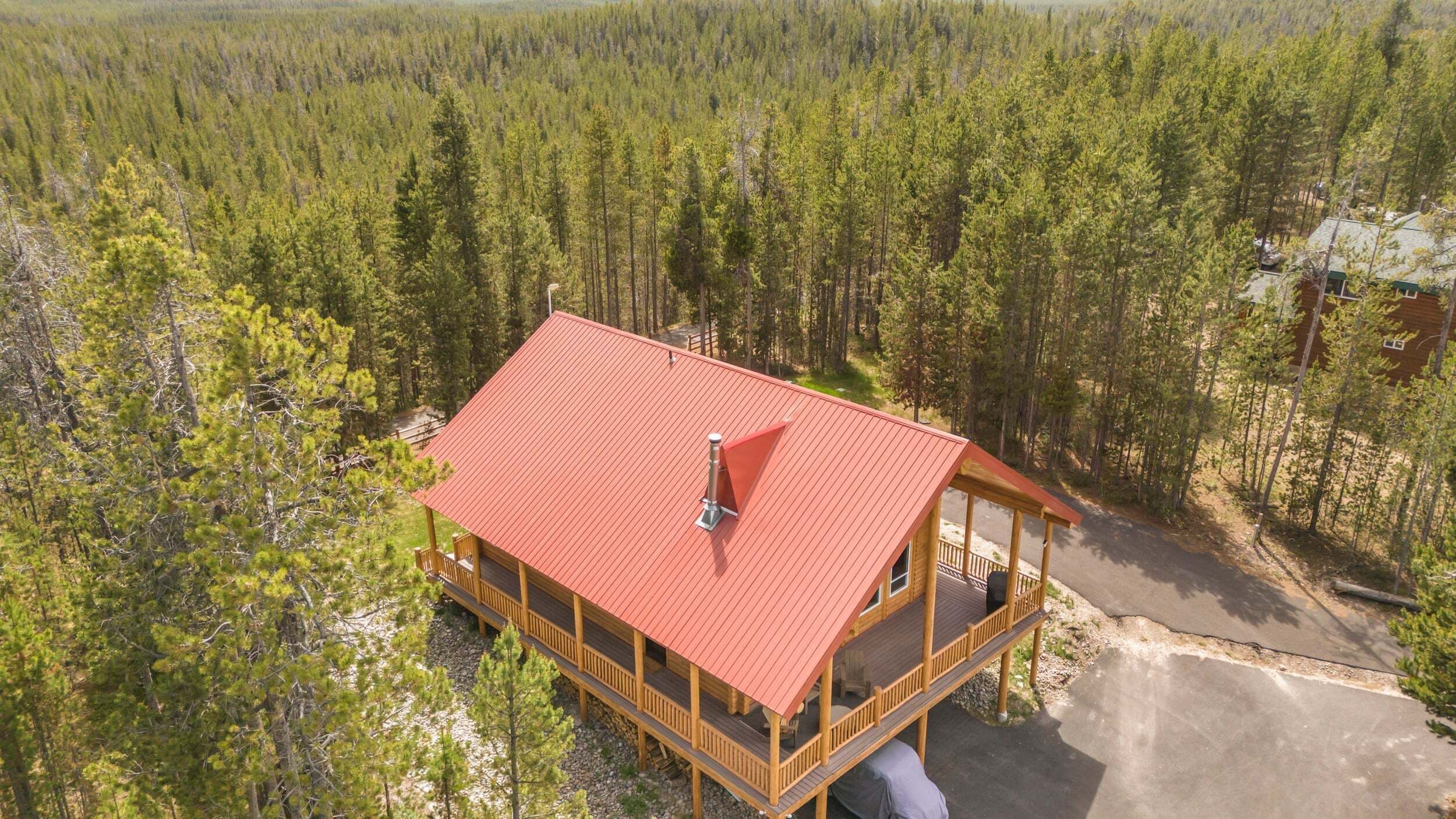 A cabin with a red roof, wooden deck, and a chimney.