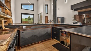 Een moderne keuken met een groot eiland, houten balken en grote ramen.