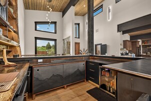 Una cocina moderna con una isla grande, vigas de madera y ventanas amplias.