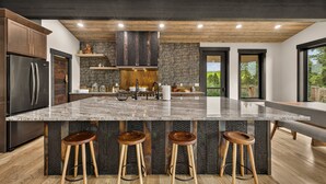 Een moderne keuken met een groot eiland, barstoelen en uitzicht op de omgeving.