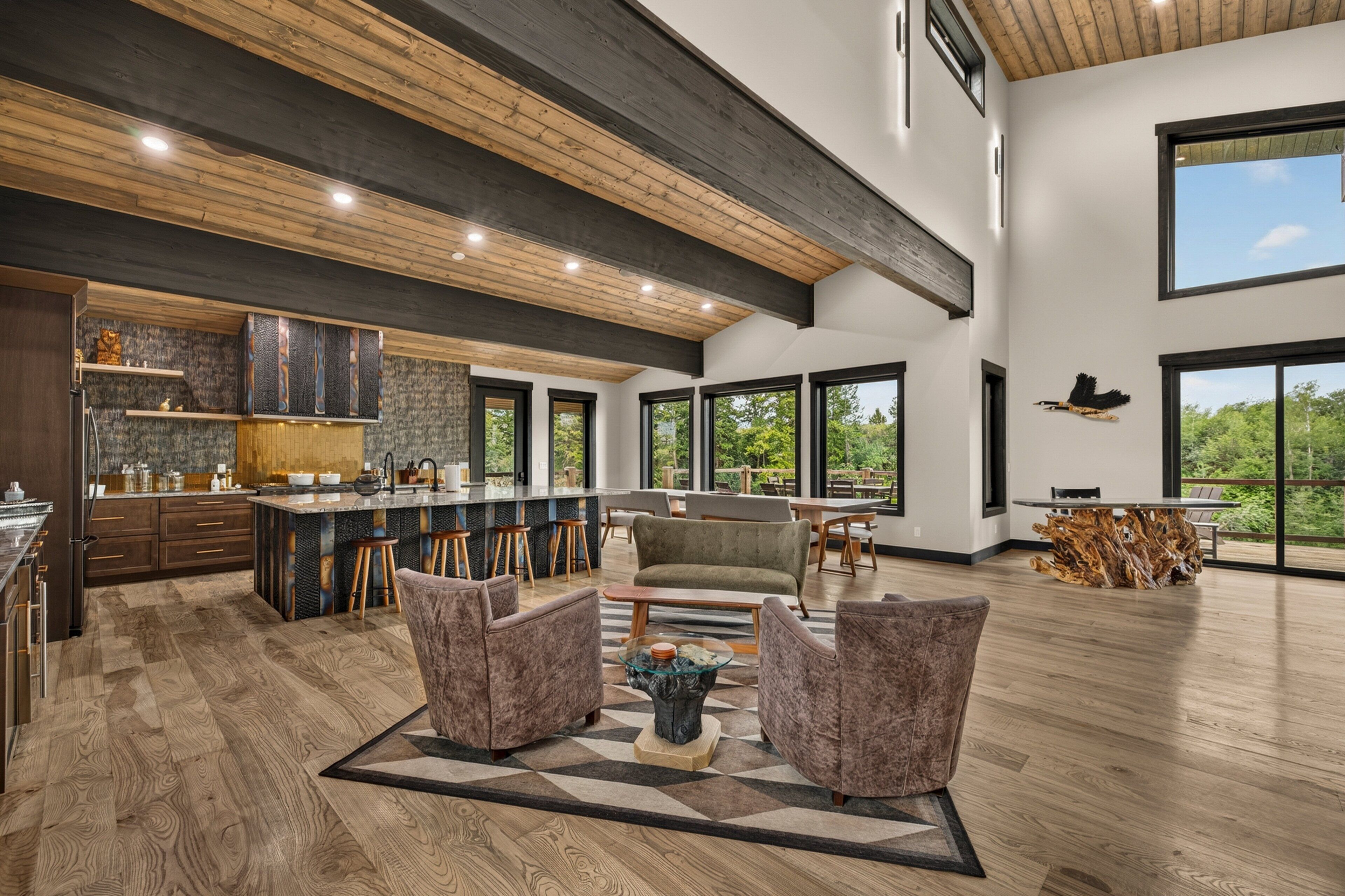 A spacious living area with a large window, a wooden ceiling, and a bar area.