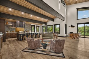 Un salón amplio con un ventanal grande, techo de madera y una zona de bar.