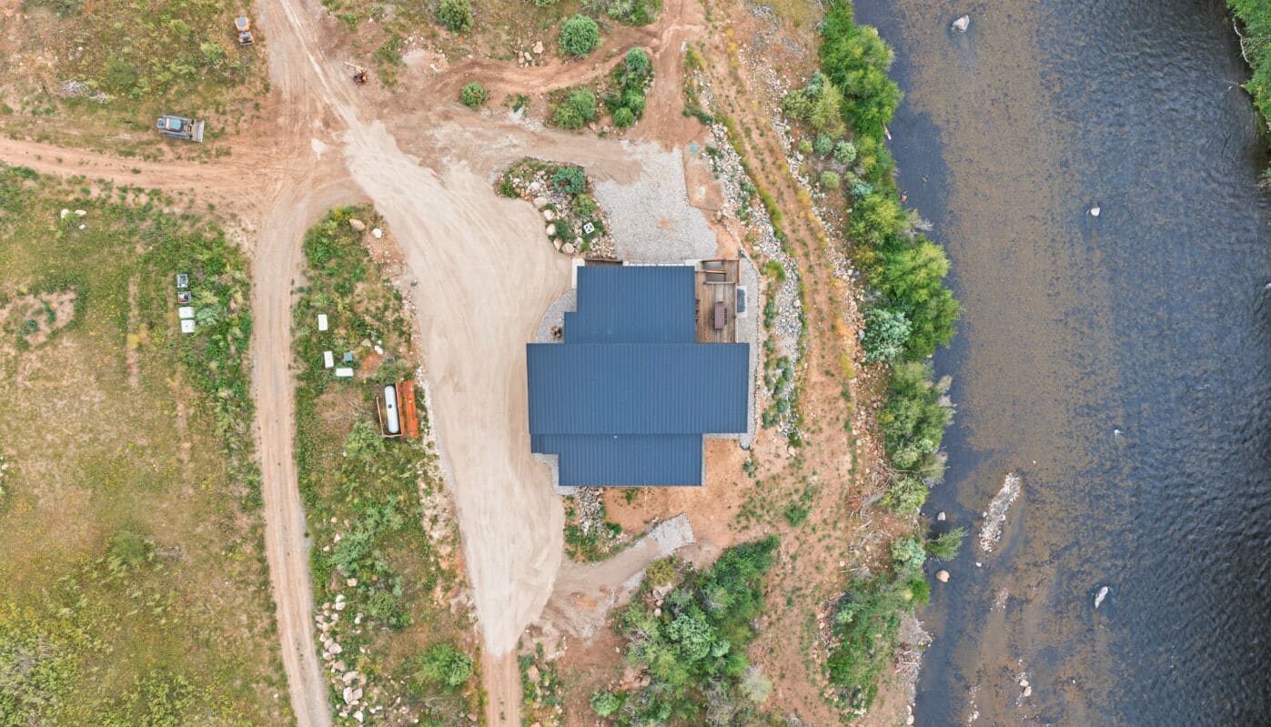 An aerial view of a property with a large building, a dirt road, and a body of water.