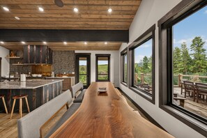Una cocina moderna con una isla grande, techo de madera y ventanas amplias que dan a una terraza.