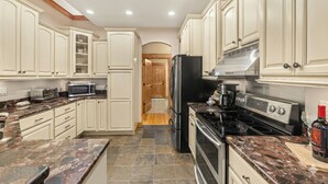 A kitchen with white cabinets, a black refrigerator, a stove, and a microwave.