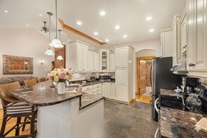 Una cocina moderna con armarios blancos, encimeras de granito y electrodomésticos de acero inoxidable.