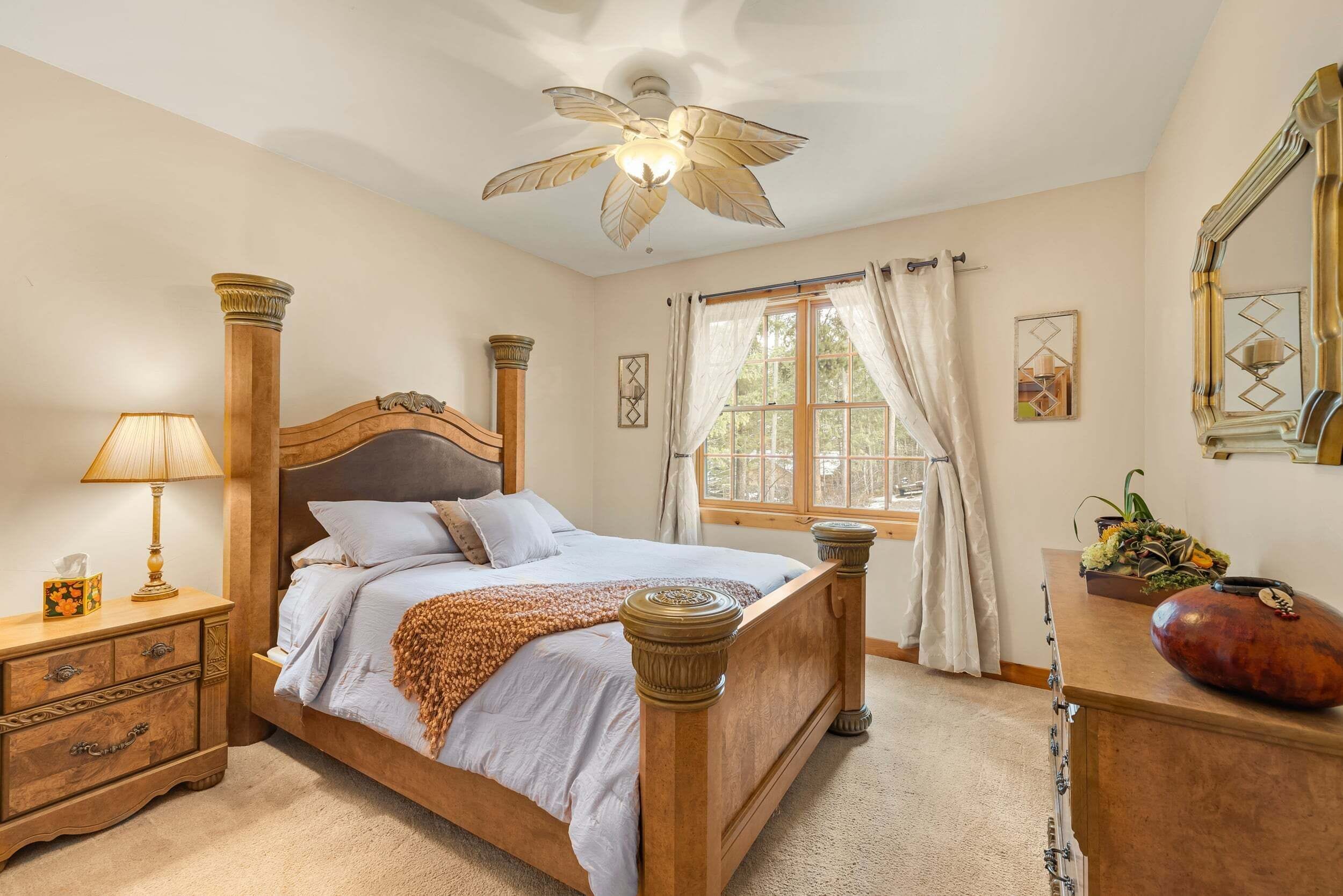 A bedroom with a bed, nightstand, lamp, window with curtains, and a dresser.