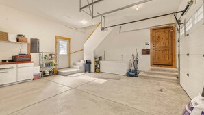 A spacious room with a concrete floor, a wooden door, and a staircase leading to an upper level.