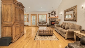 A spacious living room with a large wooden cabinet, a fireplace, a sofa, and a coffee table. - Alpine Ascent (Alpine)
