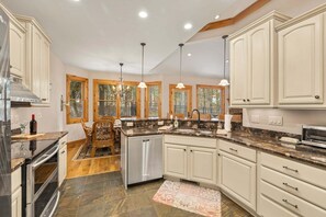 Una cocina espaciosa con una isla central, armarios de madera y un comedor con candelabro.