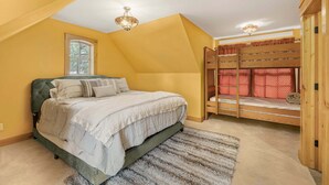 A bedroom with a bunk bed, a large window, and a ceiling fan.