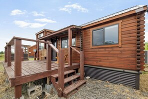 Une cabane en bois avec une véranda, un escalier et une fenêtre.