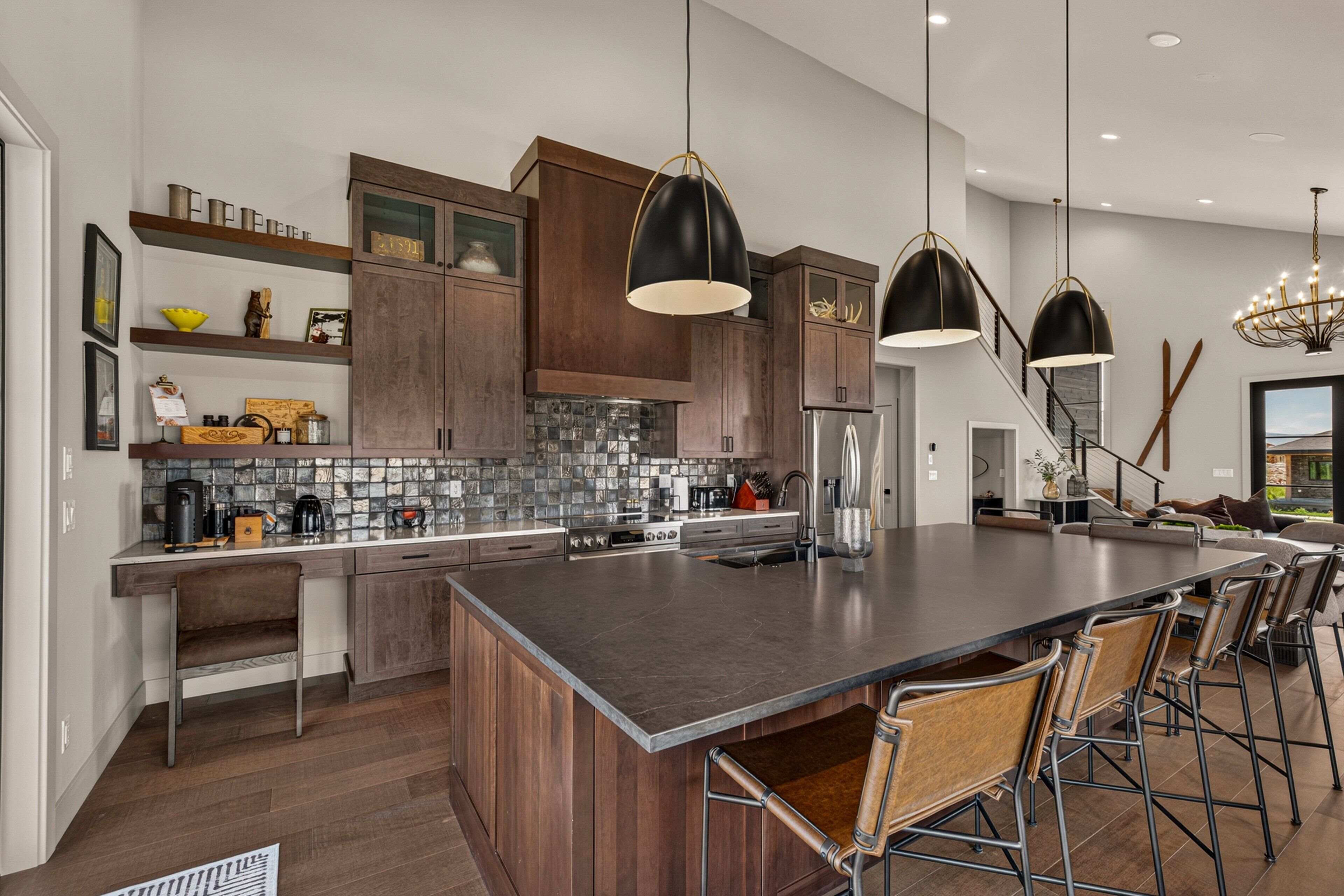 Una cocina moderna con una isla grande, armarios de madera oscura e iluminación colgante.