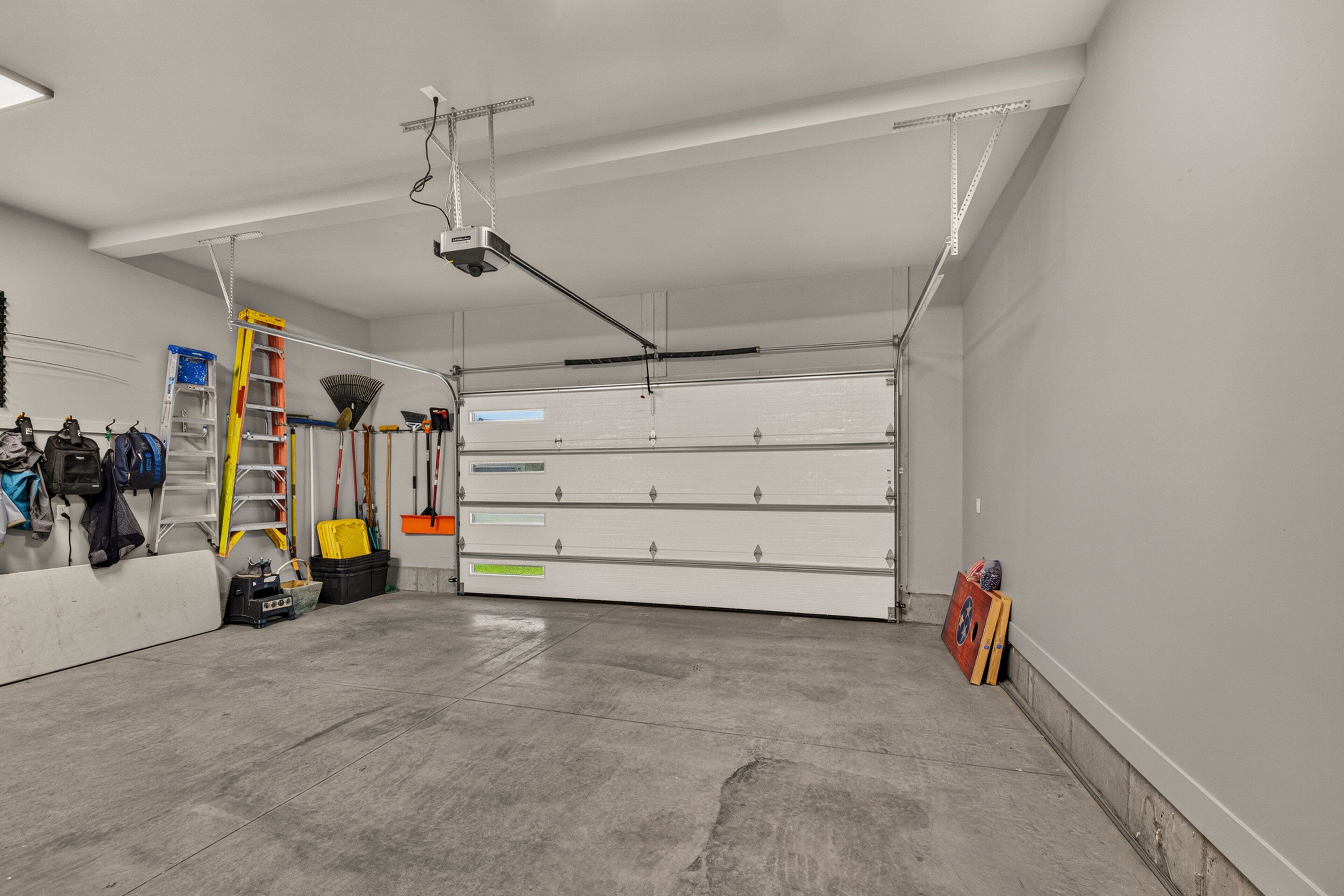 A clean, well-lit garage with a large white storage unit, a ceiling-mounted projector, and various tools and equipment.