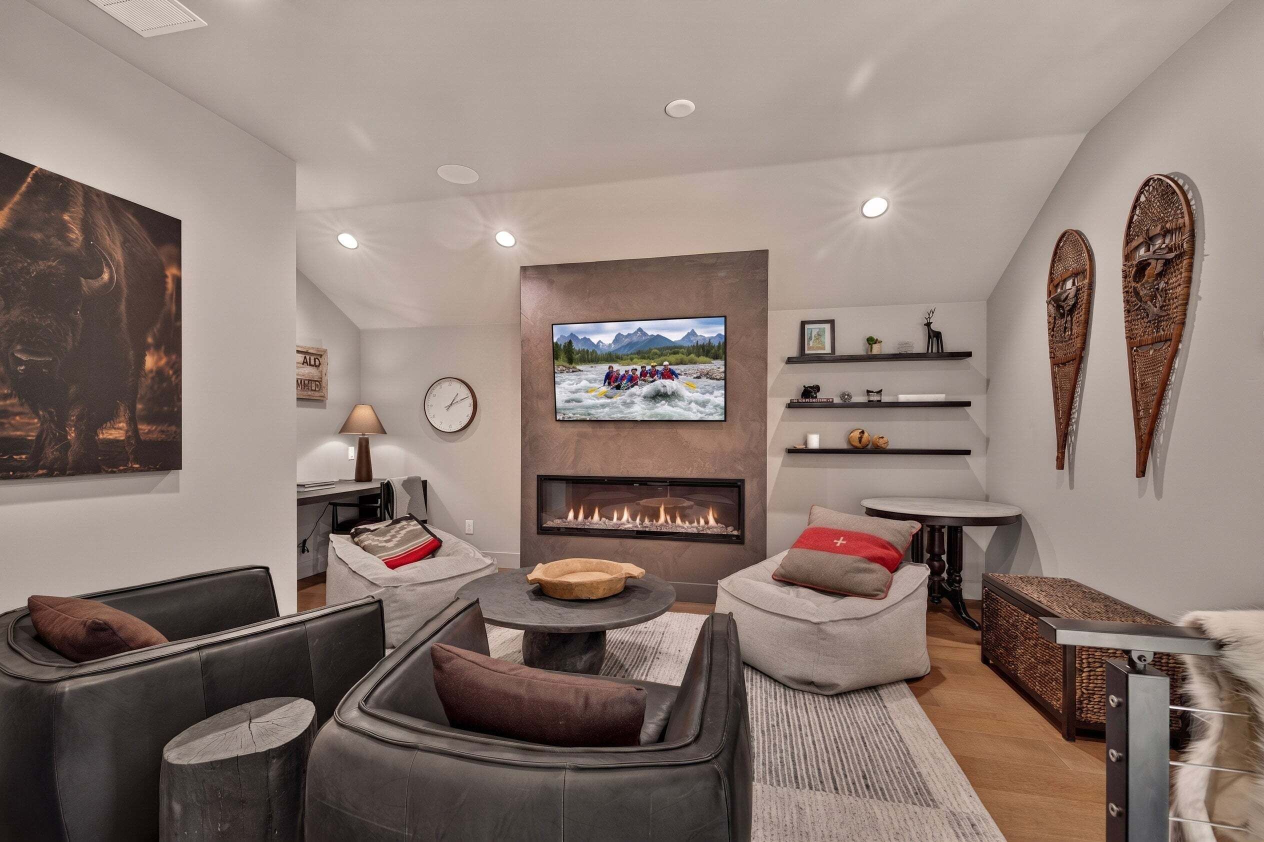 Una sala de estar moderna con chimenea, asientos cómodos, televisor y decoración en la pared.