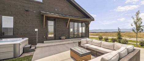A modern house with a patio area featuring outdoor furniture and a hot tub.