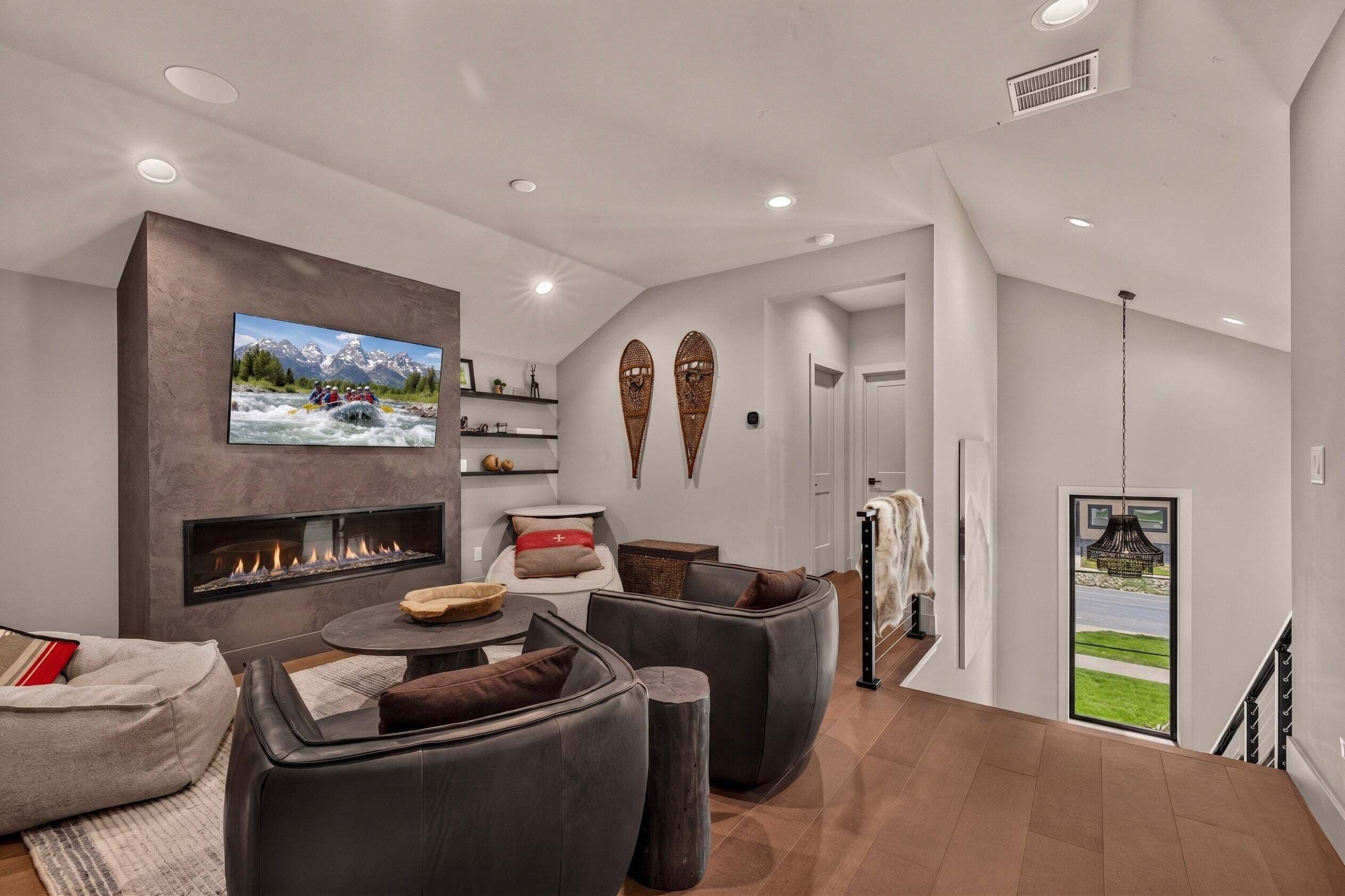 A modern living room with a fireplace, comfortable seating, a flat-screen TV, and decorative wall art.