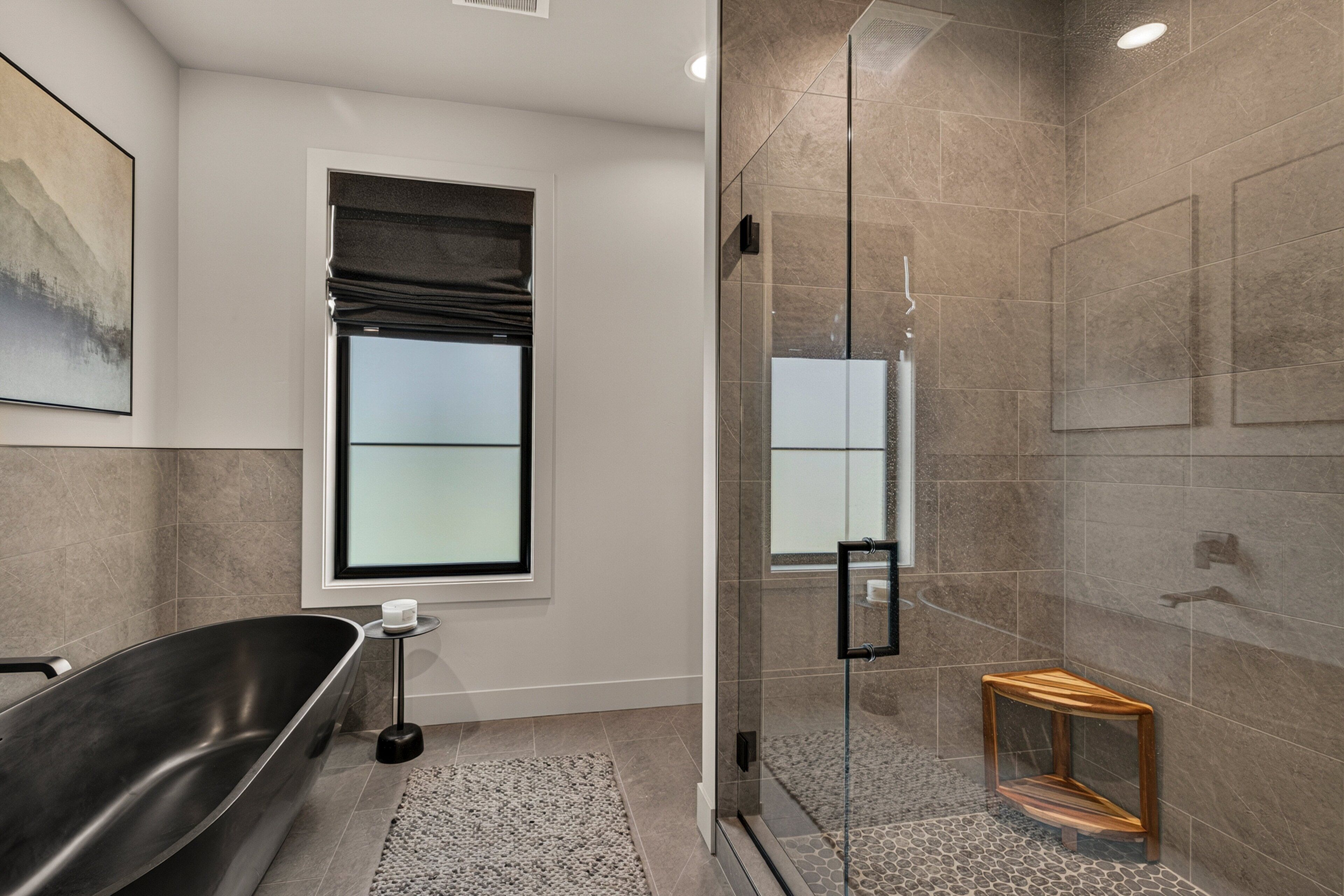A modern bathroom with a freestanding bathtub, a glass-enclosed shower, and a small wooden stool.