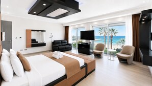 Ein modernes Hotelzimmer mit einem großen Bett, einer Sitzecke mit Blick auf den Strand und einem Flachbildfernseher.