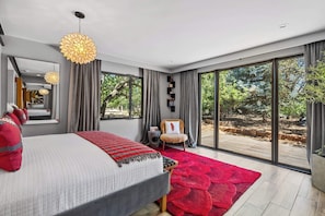 A modern bedroom with a large bed, a red rug, and a view of a garden through large windows. - Santa Fe Oasis With Three Primary Suites and Garden Nooks, Can't Miss (Santa Fe)