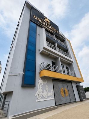 Um edifício de hotel moderno com uma placa chamativa para 'King's Kalinga' e um relevo decorativo na fachada.