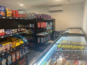 A grocery store with shelves stocked with various products including snacks, beverages, and dairy items. - Cais Eco Residence beira-mar Muro Alto (Ipojuca)