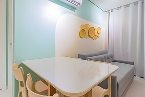 A modern room with a white table, beige chairs, a grey sofa, and a wall-mounted wooden decoration. - Cais Eco Residence beira-mar Muro Alto (Ipojuca)